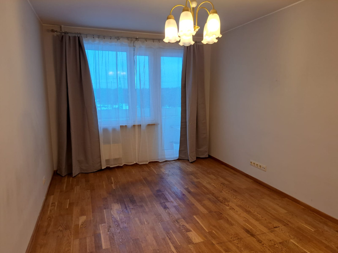Gaiša istaba ar lielu logu un aizkariem.