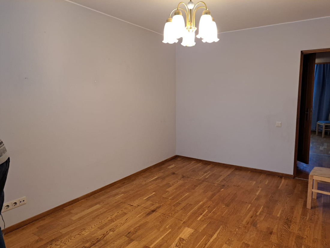 Tukša istaba ar koka grīdu un lustrām.