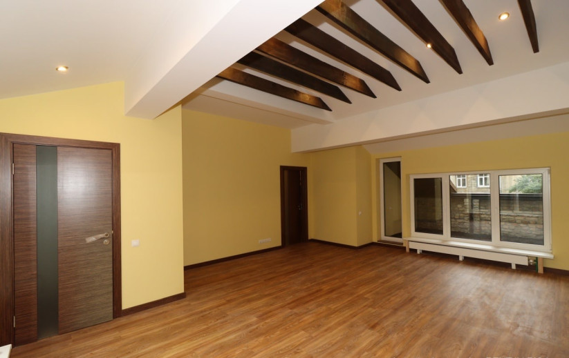 Spacious room with yellow walls and beams.