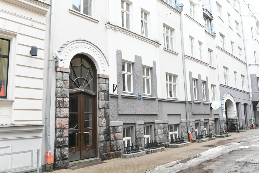 Ēkas fasāde ar akmens apdari un ieeju.