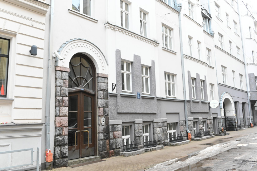Ēkas fasāde ar akmens apdari un ieeju.