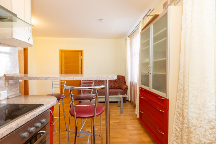 Kitchen with counter table and red chairs.
