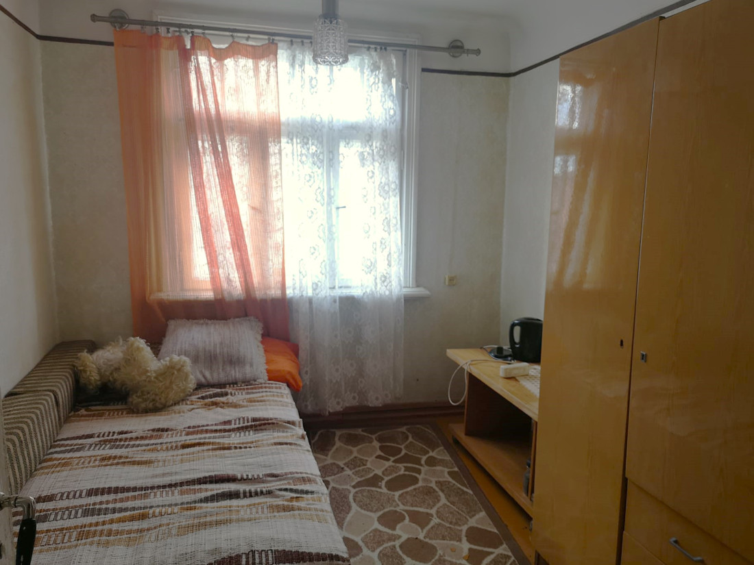 Gaiša istaba ar gultu un skapīti.
