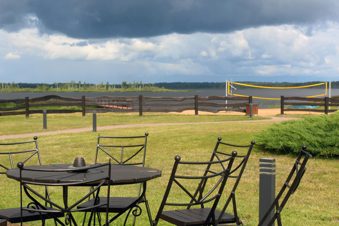 Garden furniture by lake with volleyball court.