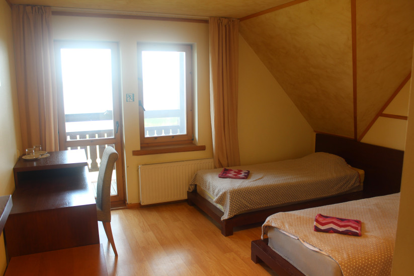 Twin bedroom with desk and balcony.