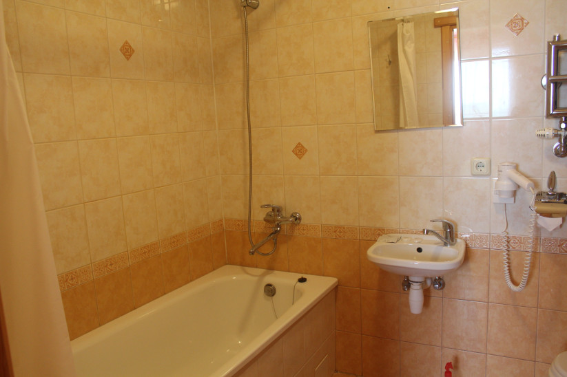 Bathtub and sink with a hairdryer.