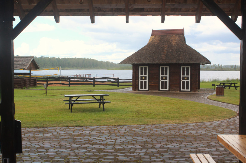Thatched-roof hut near a lake.