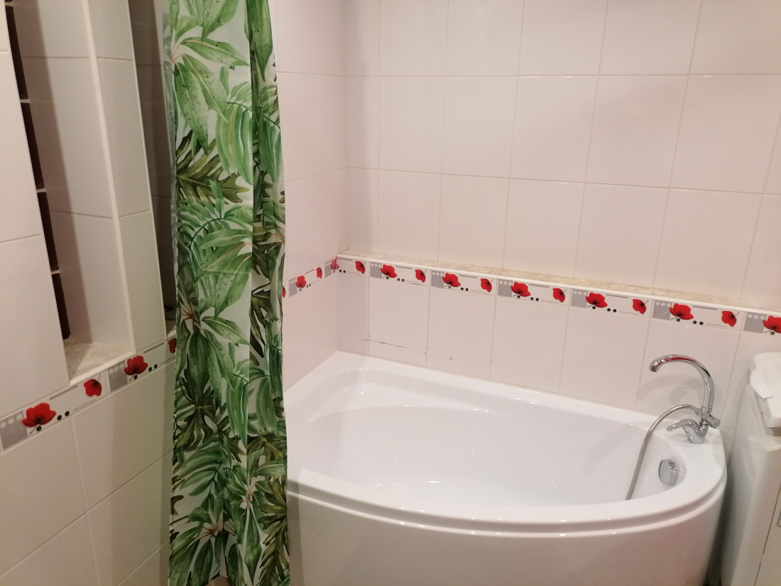 Bathtub with green shower curtain.