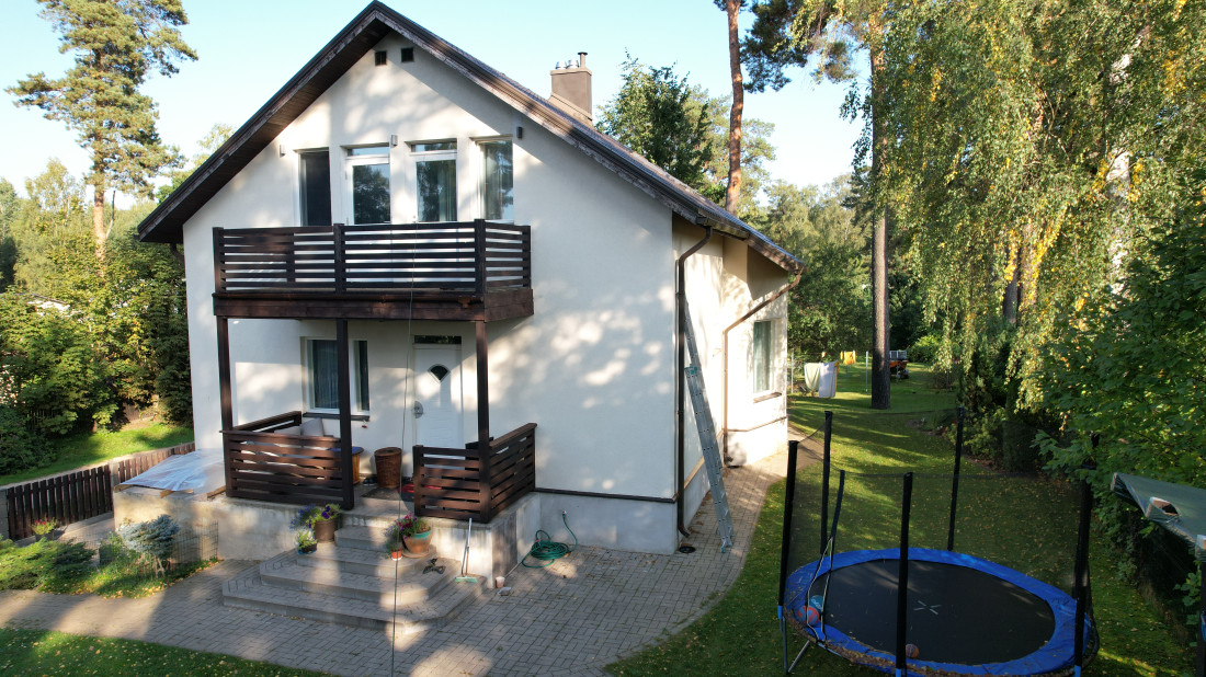 Mājas pagalms ar zaļu teritoriju un bērnu rotaļlaukumu.