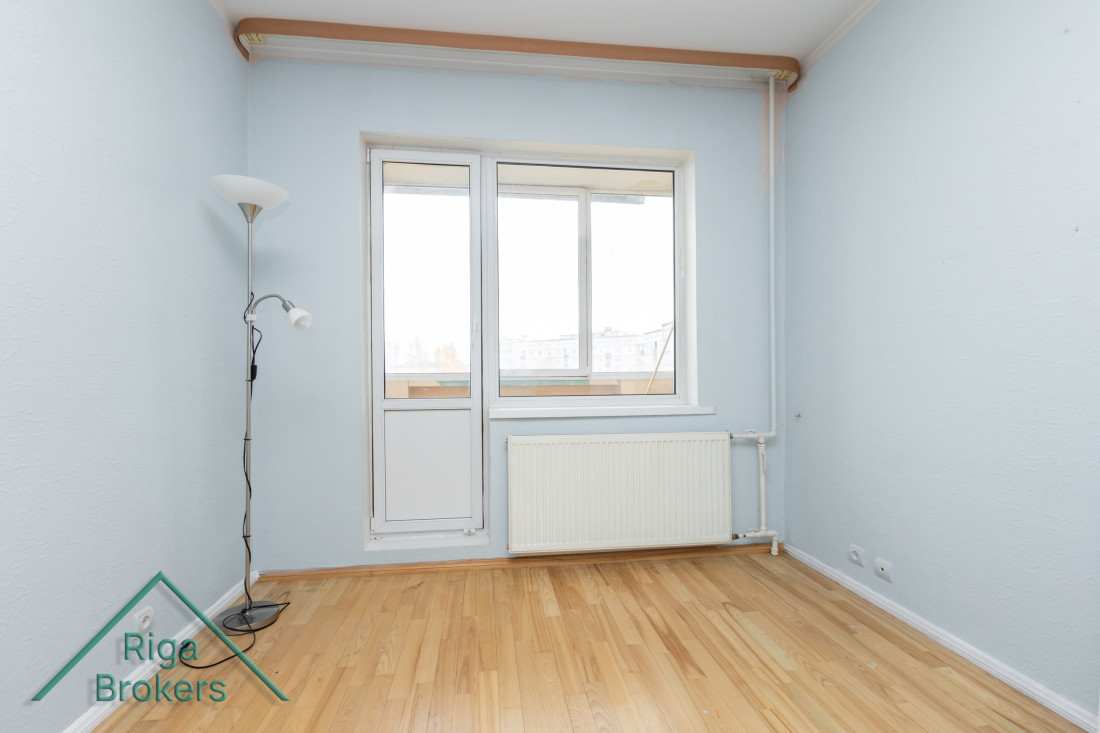 Istaba ar durvīm uz balkonu un radiatoru.