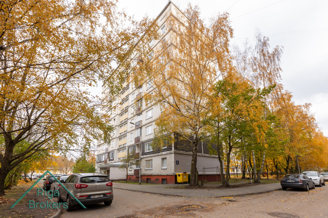 Daudzdzīvokļu ēka rudenī ar dzeltenām lapām.