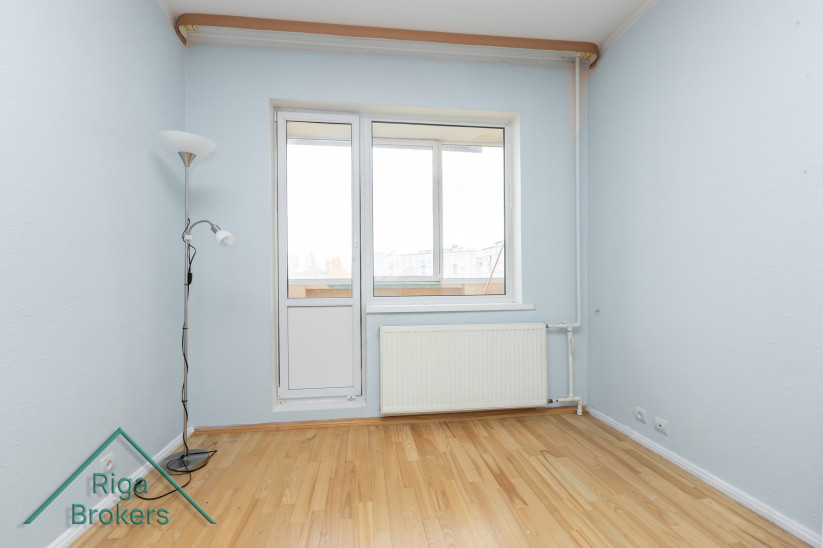 Istaba ar durvīm uz balkonu un radiatoru.