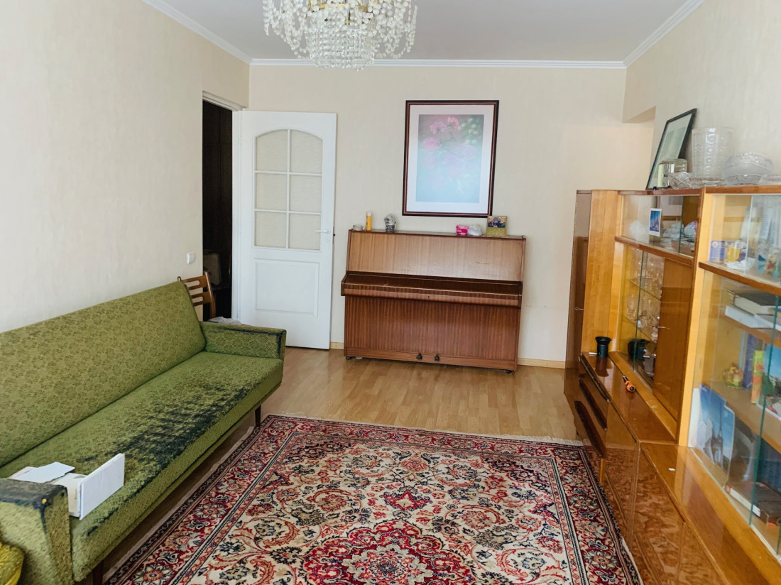 Living room with green sofa and piano.