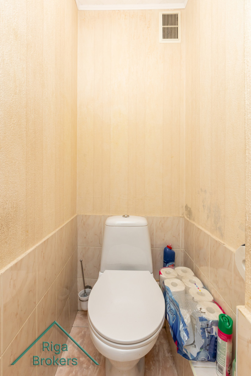 Toilet room with white toilet and shelf.