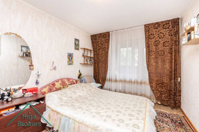 Bedroom with curtains and floral bedspread.