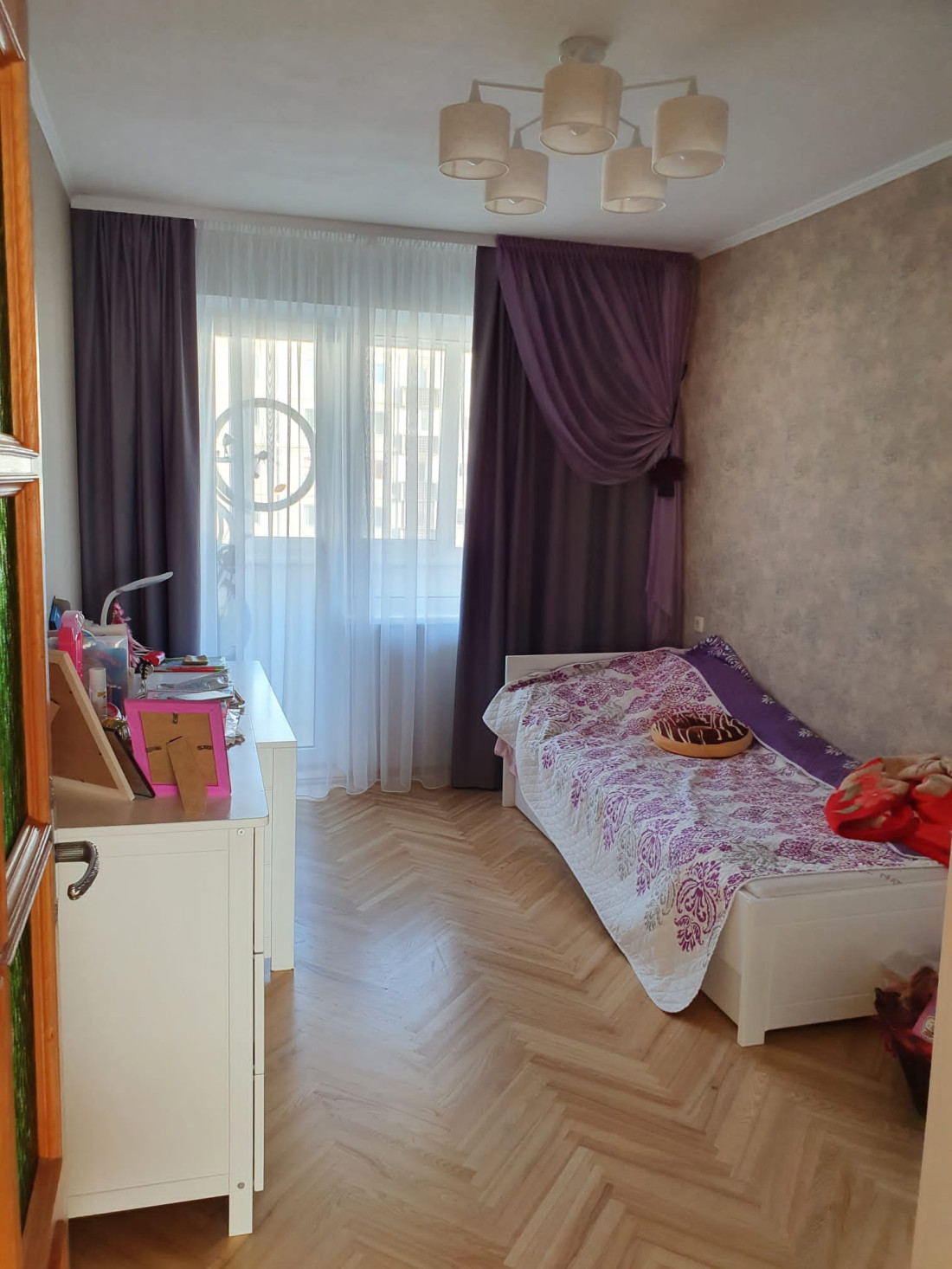 Room with purple curtains and a single bed.