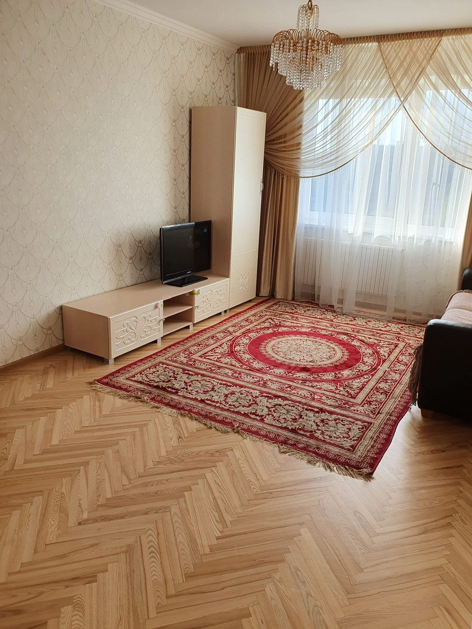 Living room with an elegant carpet and crystal chandelier.
