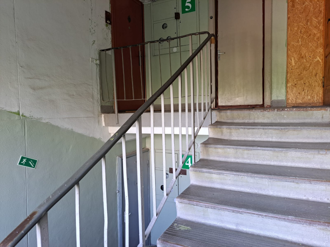 Stairwell with signs and apartment doors.