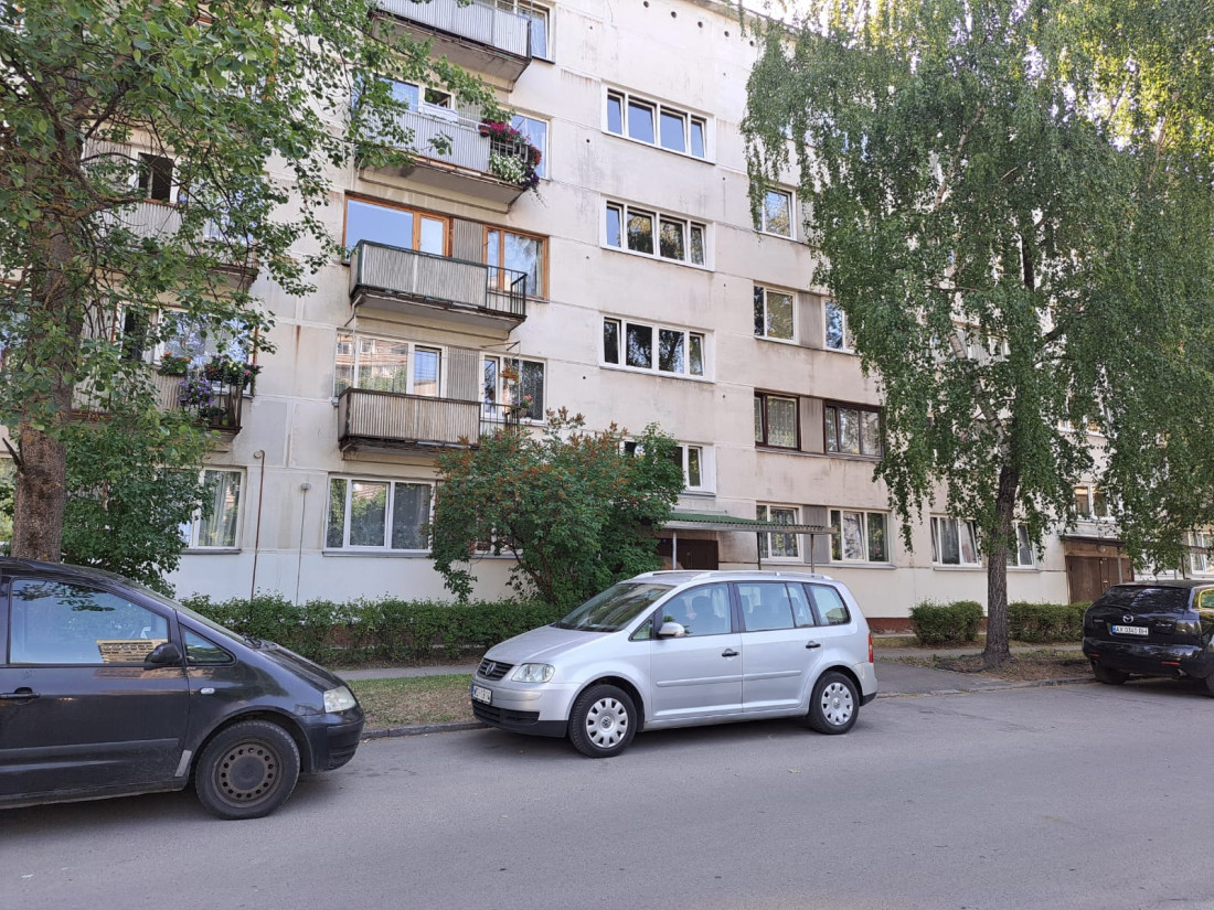 Apartment building with cars and trees.
