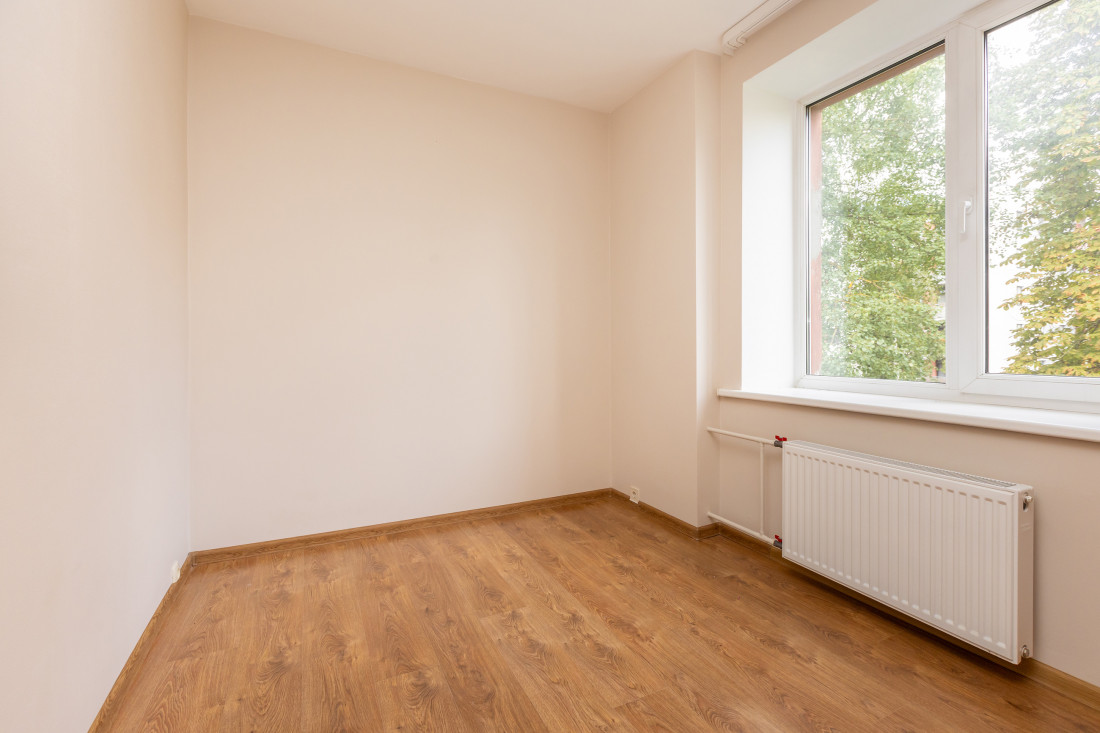 Tukša istaba ar logu un radiatoru.