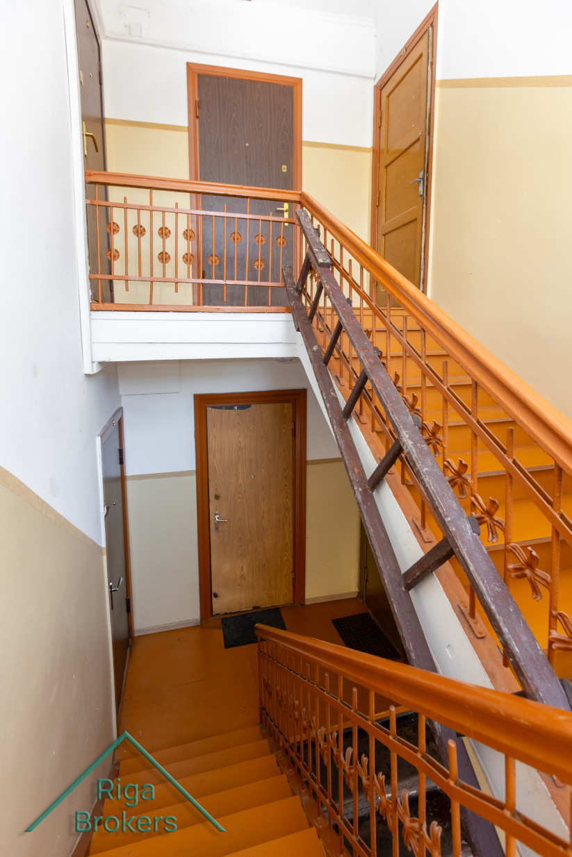 Stairwell of an apartment building with orange railings.