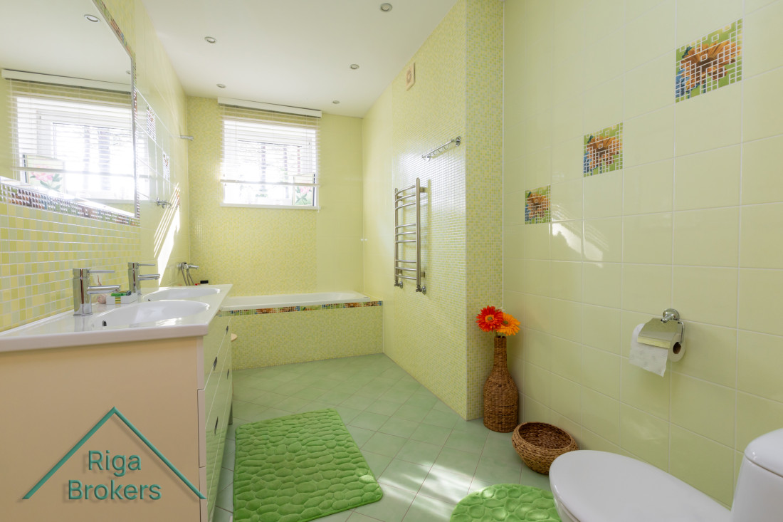 Yellow bathroom with two sinks and bathtub.