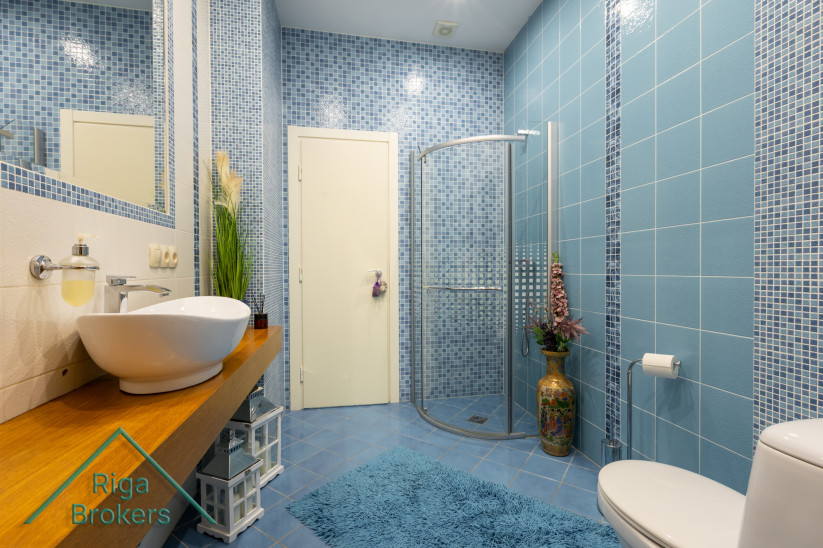 Blue tiled bathroom with shower and sink.