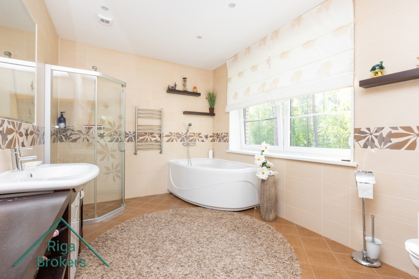 Spacious bathroom with corner bathtub and window.
