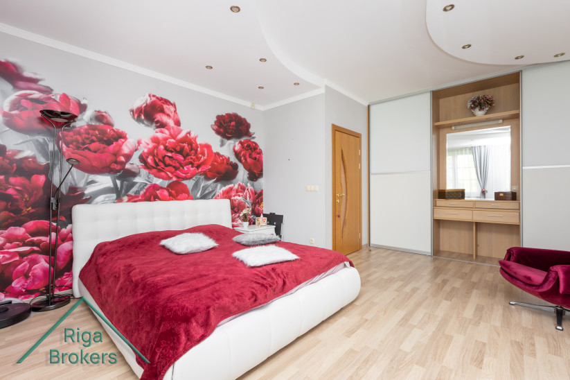 Bedroom with red bedspread and floral wallpaper.