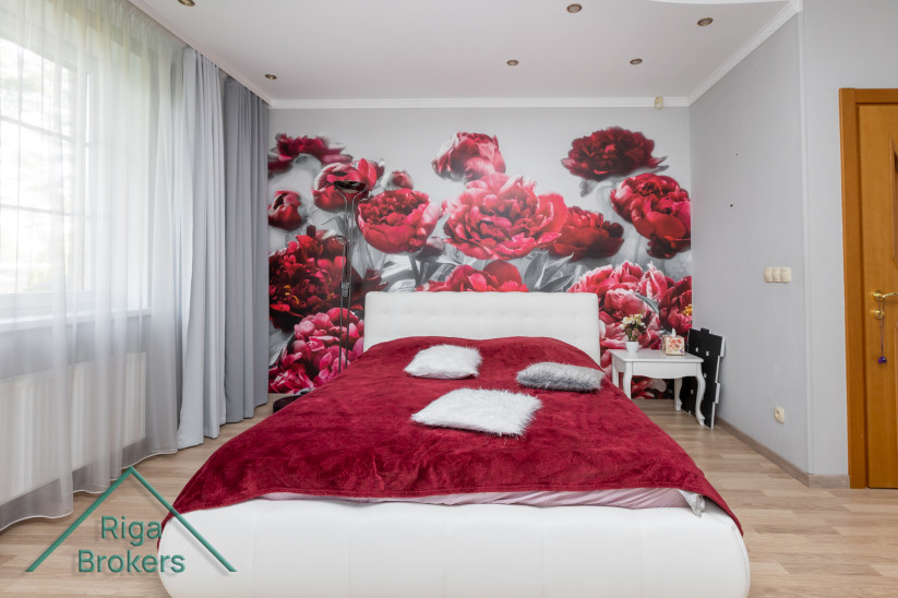 Bedroom with red bedspread and floral wall.