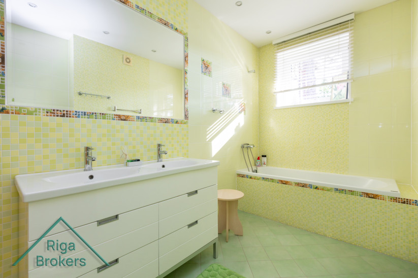 Yellow bathroom with bathtub and large mirror.