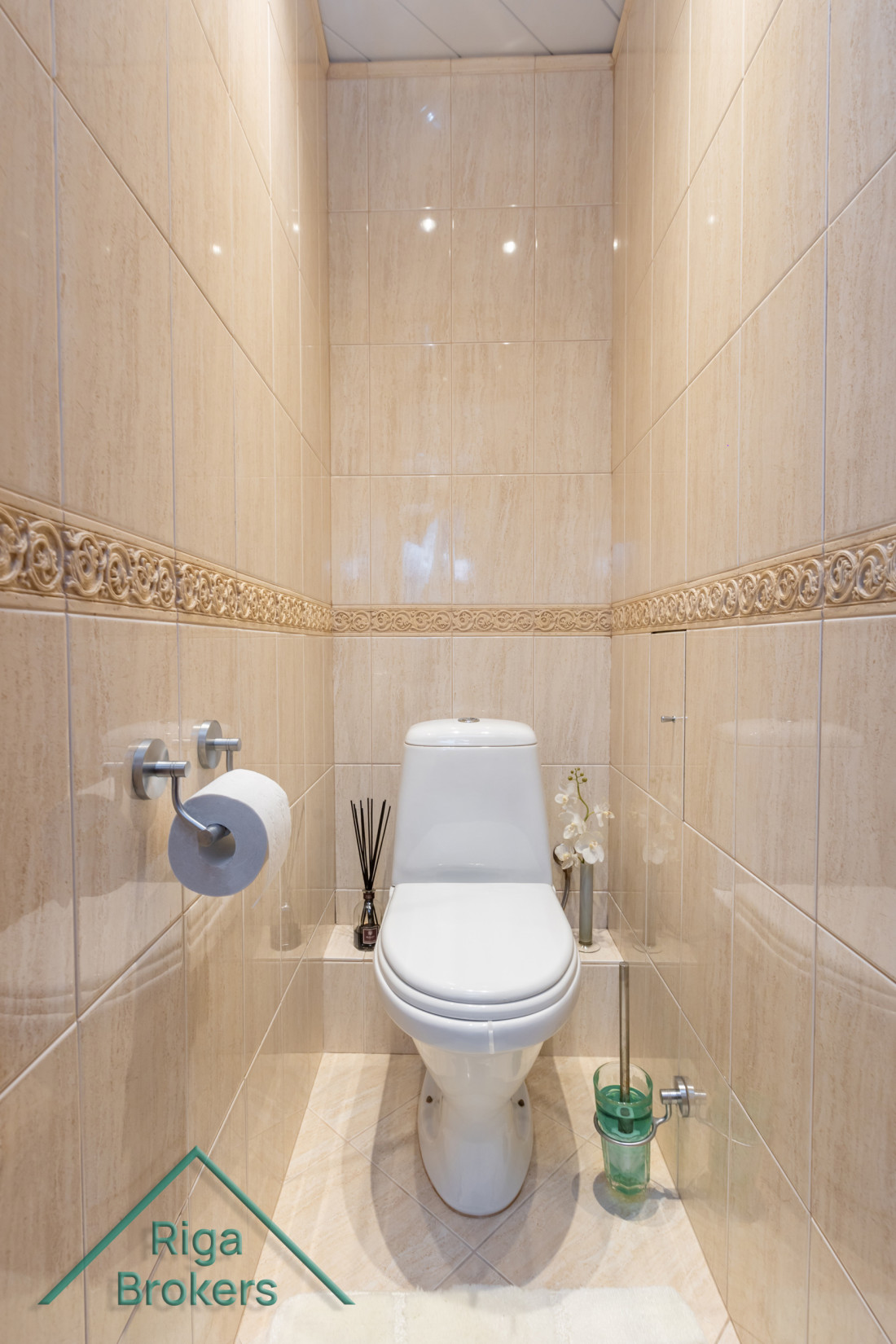 Toilet with ceramic tiles and decor.
