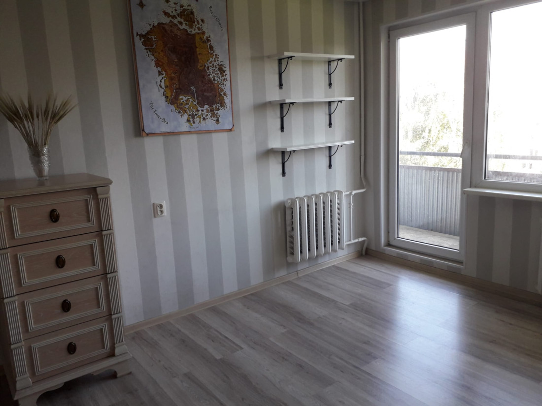 Dzīvojamā istaba ar balkonu un plauktiem.