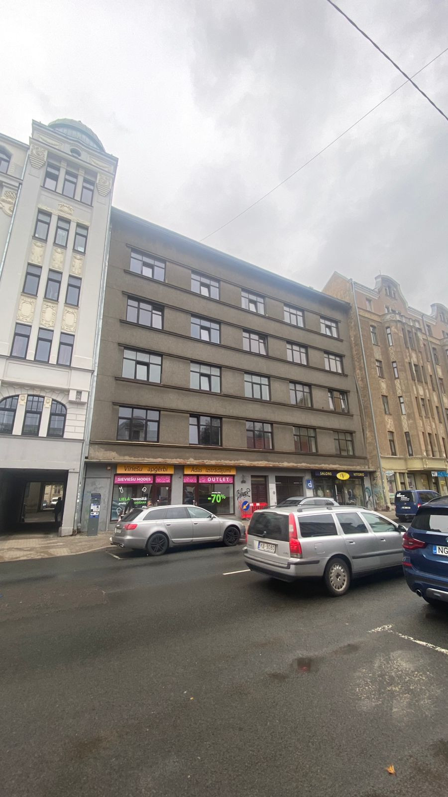 Building with storefronts and parked cars.