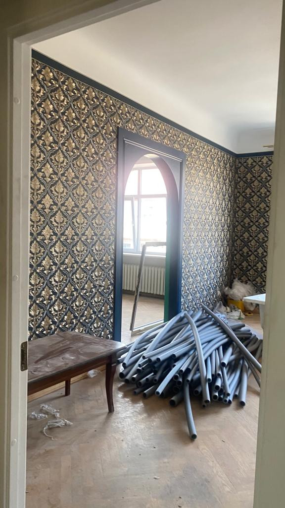 Room with decorative wallpaper and pipes.