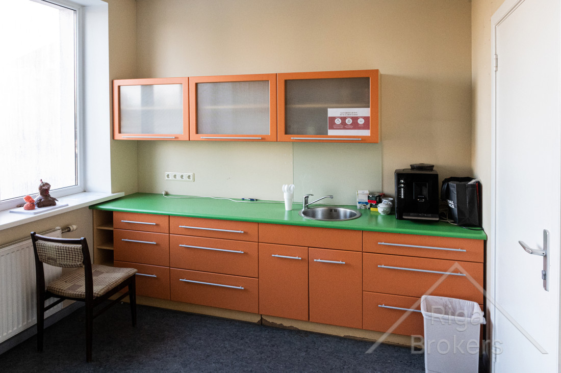 Birojā ir virtuves telpa ar virtuves iekārtām, skapīšiem, krēslu un miskasti