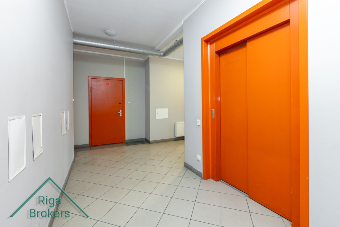 Bright corridor with orange doors and elevator.