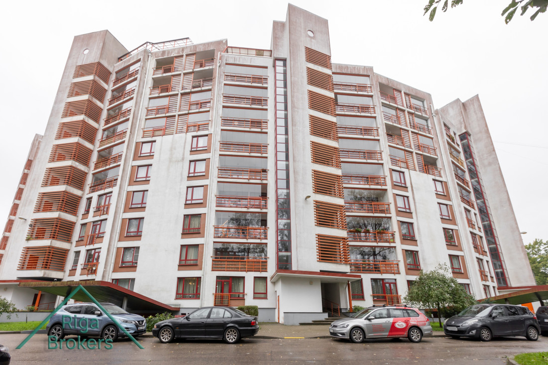 Residential building with red details and parked cars.