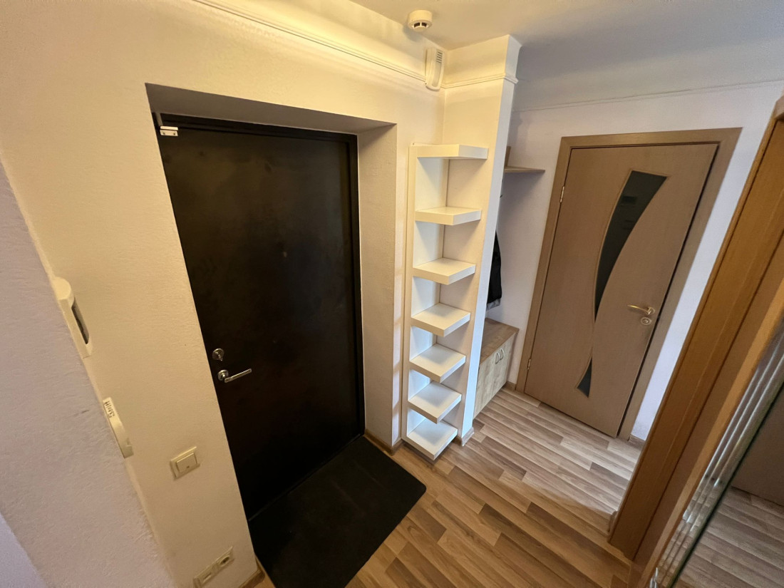 Hallway with black door and shelves.