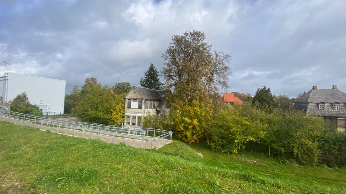 Veca māja ar kokiem priekšplānā.