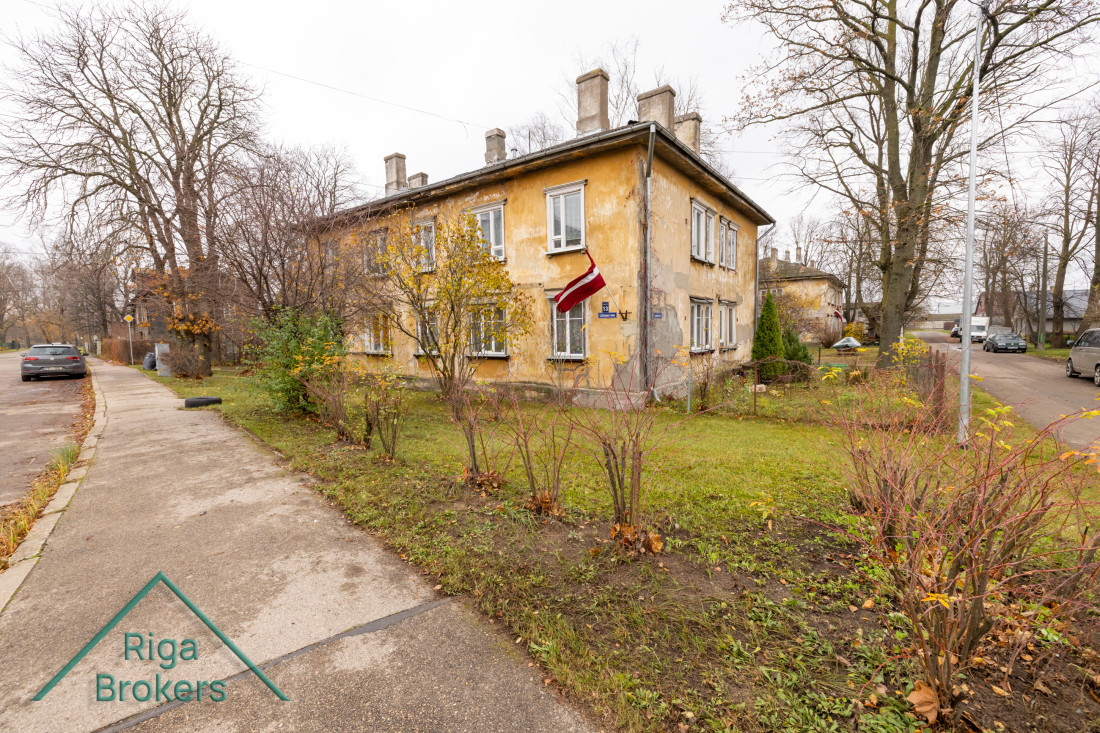 Dzeltena māja ar Latvijas karogu pie ieejas.