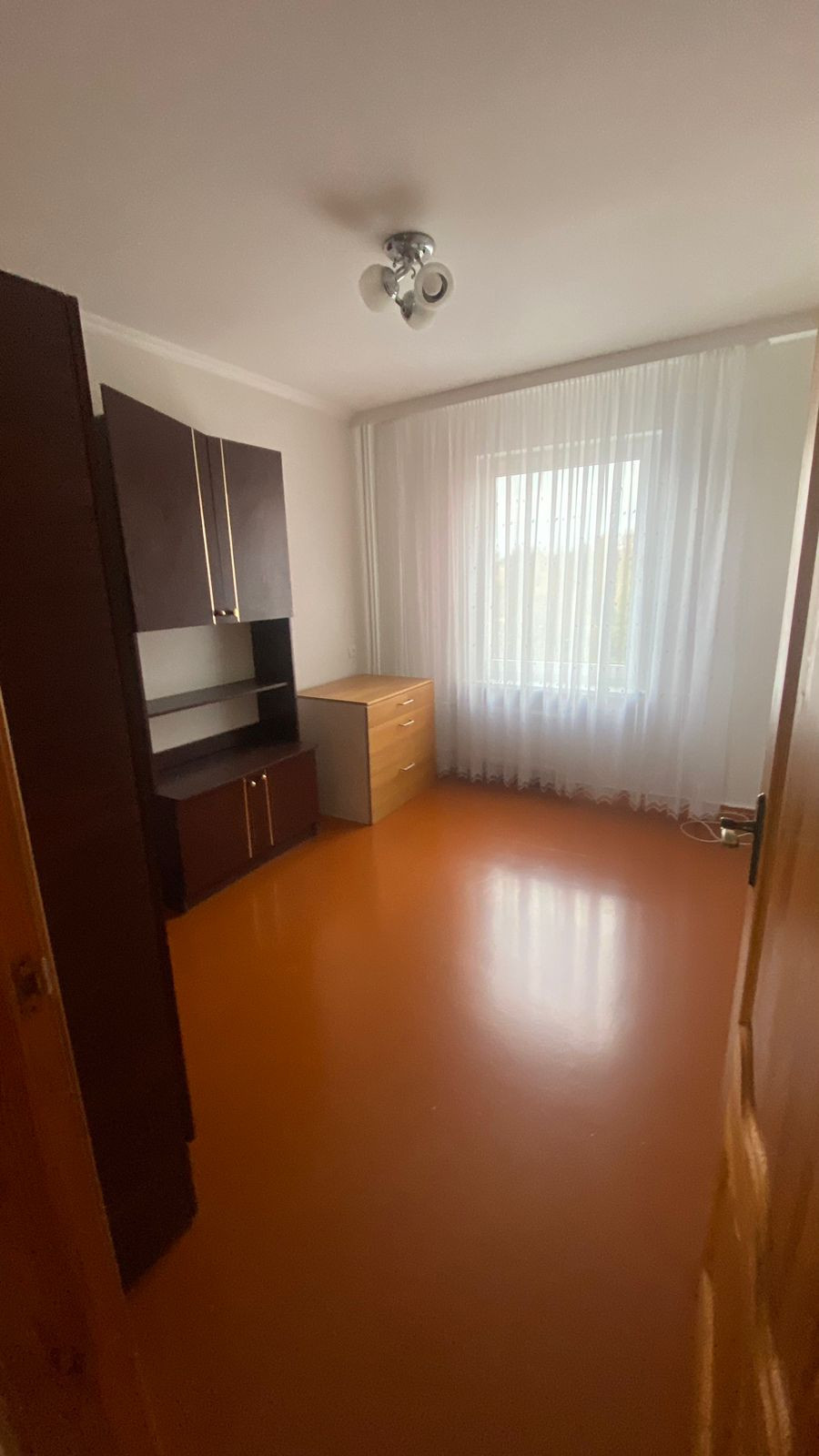 Room with a desk and curtains.
