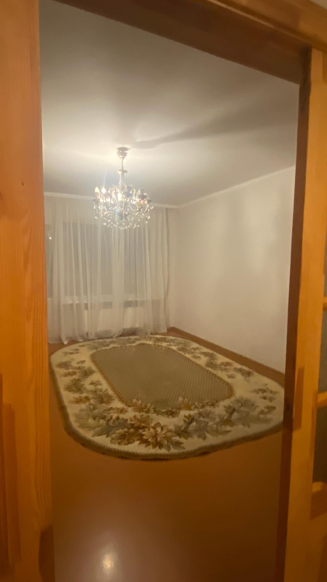 Spacious room with chandelier and carpet.