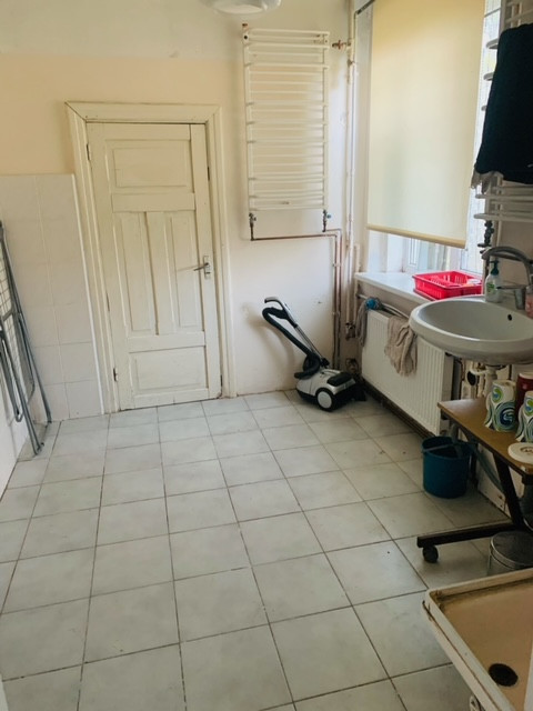 Veļas mazgātava ar izlietni un radiatoru.