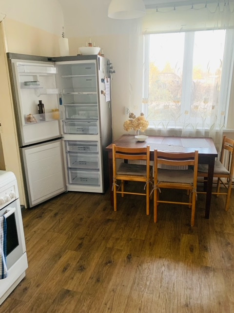 Virtuves zona ar ledusskapi un ēdamgaldu.