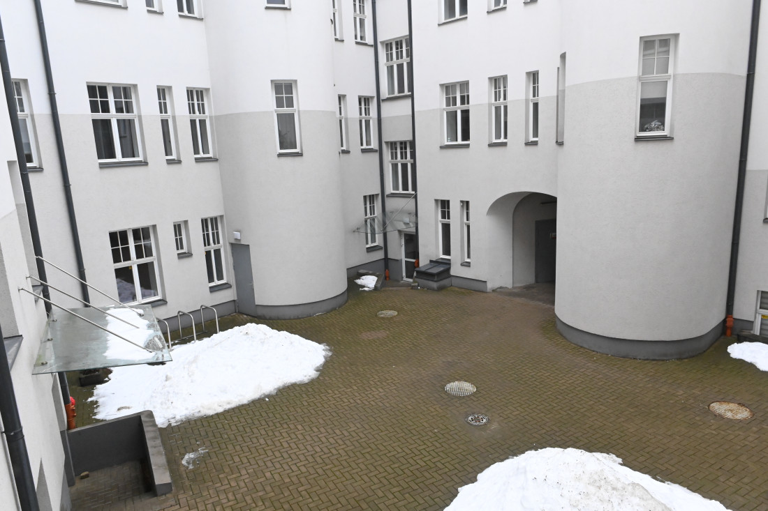Mājas iekšpagalms ar bruģētu zonu un sniegu.