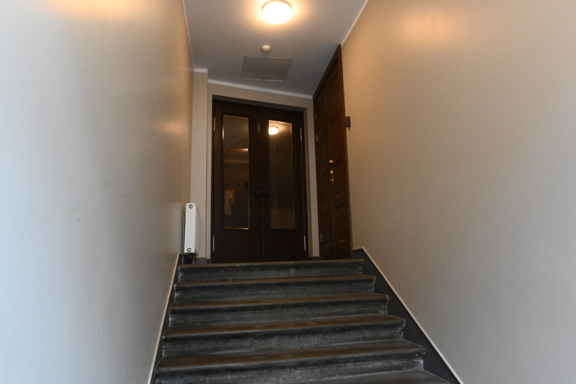 Kāpņu telpa ar stiklotām durvīm.