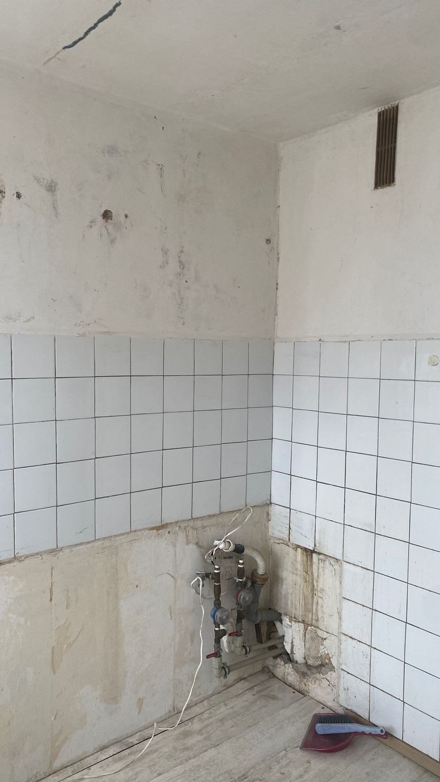 Tukša virtuve ar vecām flīzēm un caurulēm.