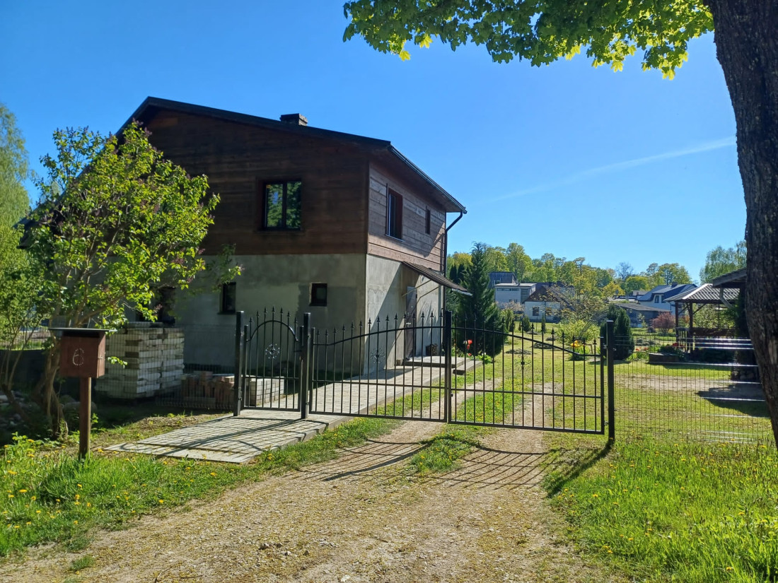 Mājīgs divstāvu mājas priekšskats ar vārtiem. 