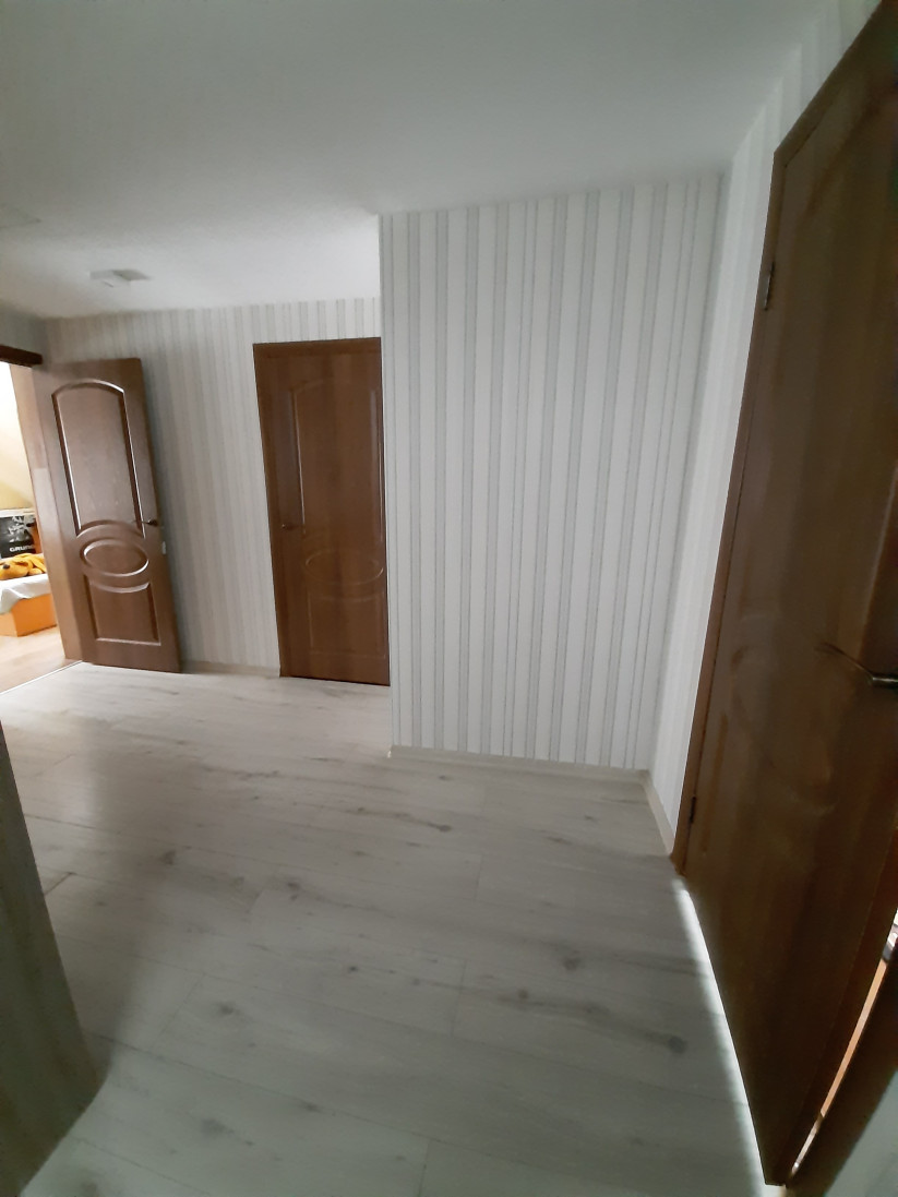 Garš un šaurs gaišs koridors ar koka grīdu